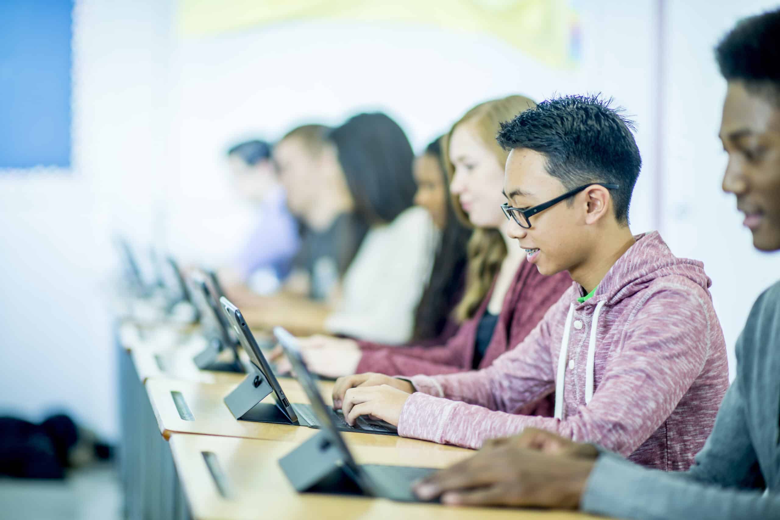 Estudiantes que usan tabletas en clase sentados en sus escritorios
