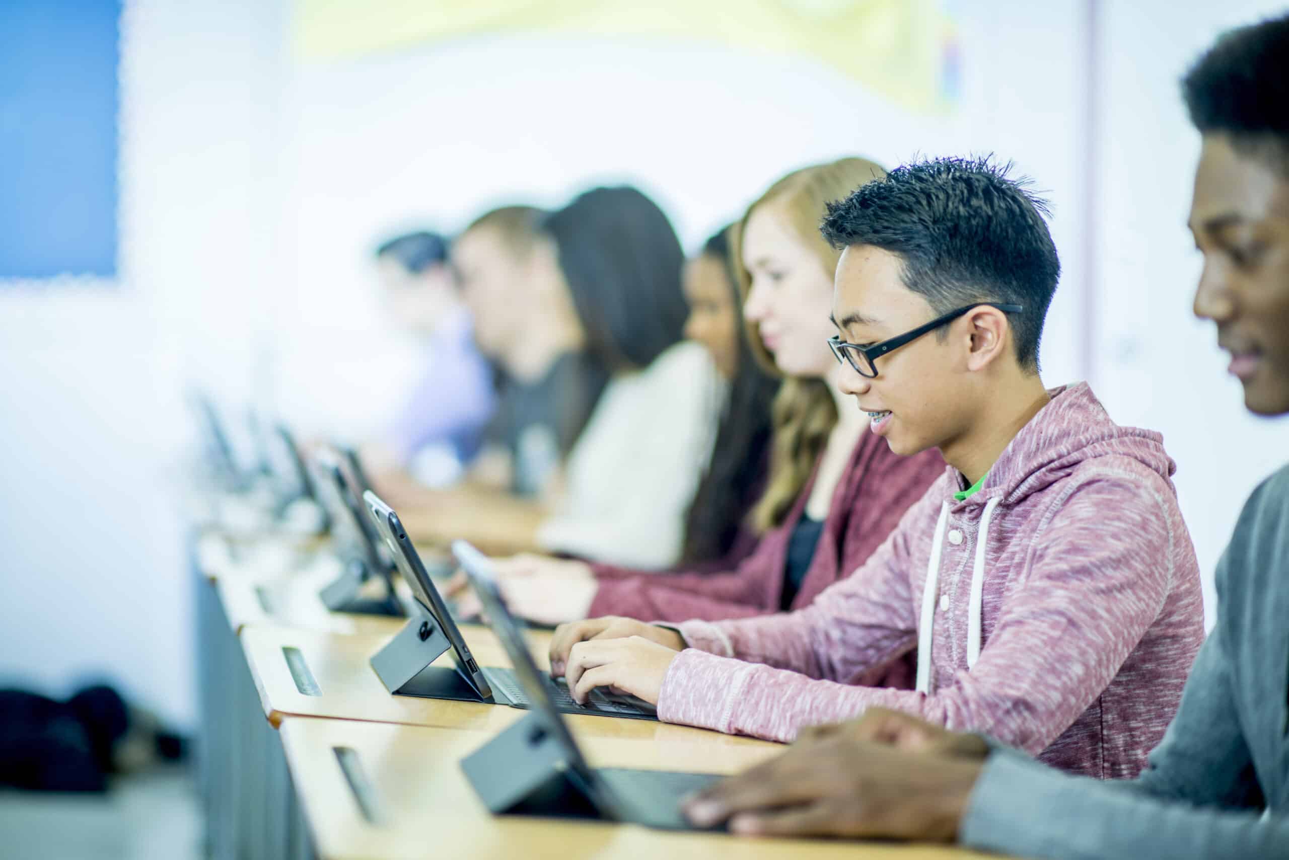 Students using tablets in class sitting at their desks