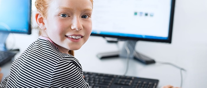 flicka på stationär dator som vänder sig leende