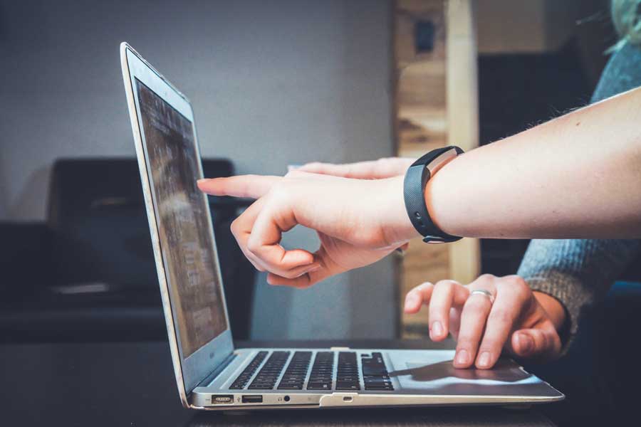 Two individuals working together and pointing at a computer screen