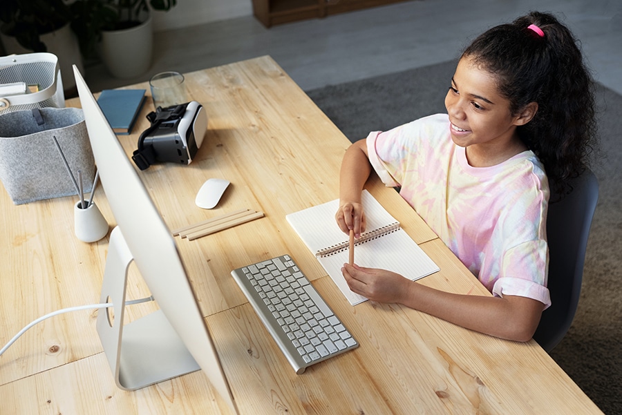 Mädchen im rosa Hemd schaut auf den iMac