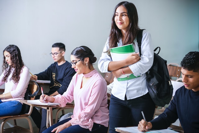 Smiling female student standing in a classroom; Lightspeed Alert adds Spanish Language Capabilities.