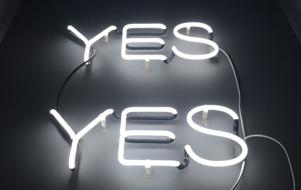 Black and white photo of two neon signs, each spelling the word, "YES."
