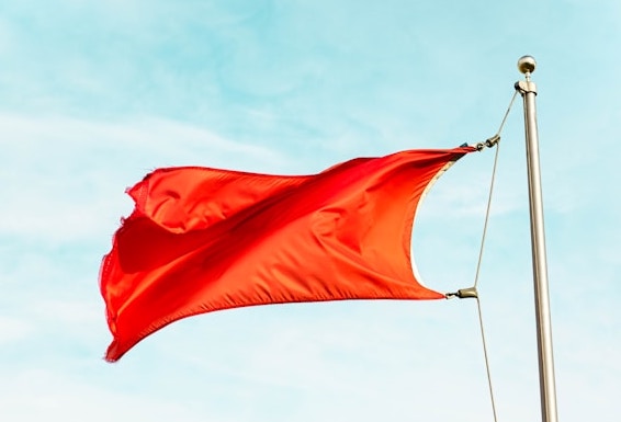Bild av en röd flagga vajar i vinden. Skyddar integritet av studentdata.